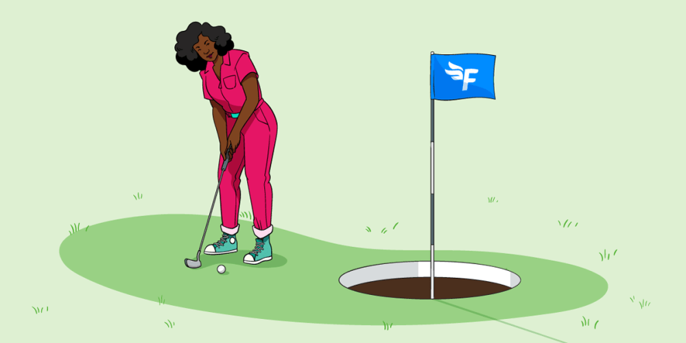 A woman in a red jumpsuit is aiming to putt a golf ball into a hole on a golf course. The hole is massive and there’s a FreeAgent flag flying from it - so she should easily manage to hit her target.