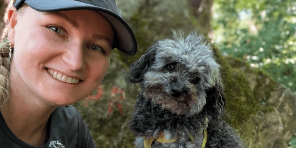 Boguslawa Babijczuk of Bea's Pet Care Services in Bristol smiles beside a small grey dog.