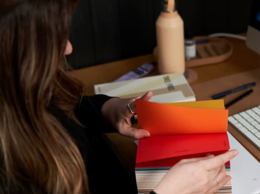Lisa flicking through a book of colour samples at her desk.