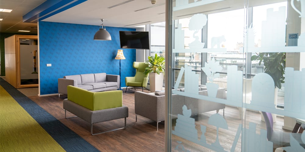 View of the FreeAgent office including a flexible collaboration area with sofas and glass wall.