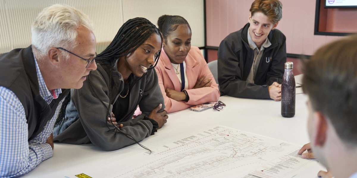 Photo of 5 Utility Results employees sitting round a table and looking at an infrastructure map.