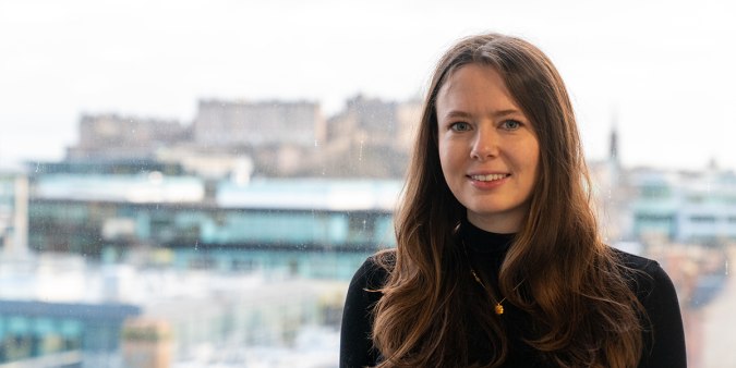 Photo of Kate in the FreeAgent office with Edinburgh castle in the background. 